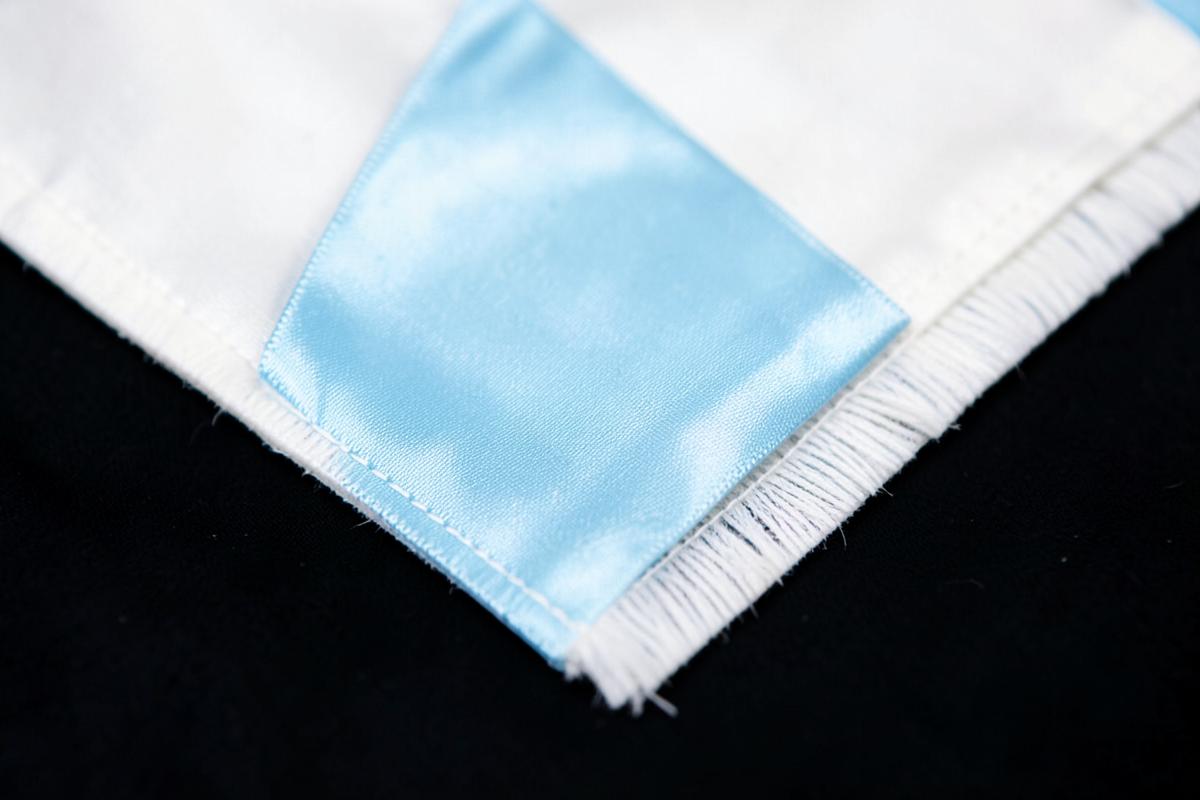 Avental branco com fita azul-clara sobre fundo escuro