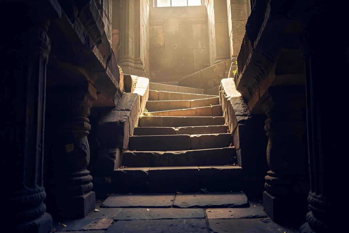 Escada de degraus de pedra em templo antigo subindo em direção à luz