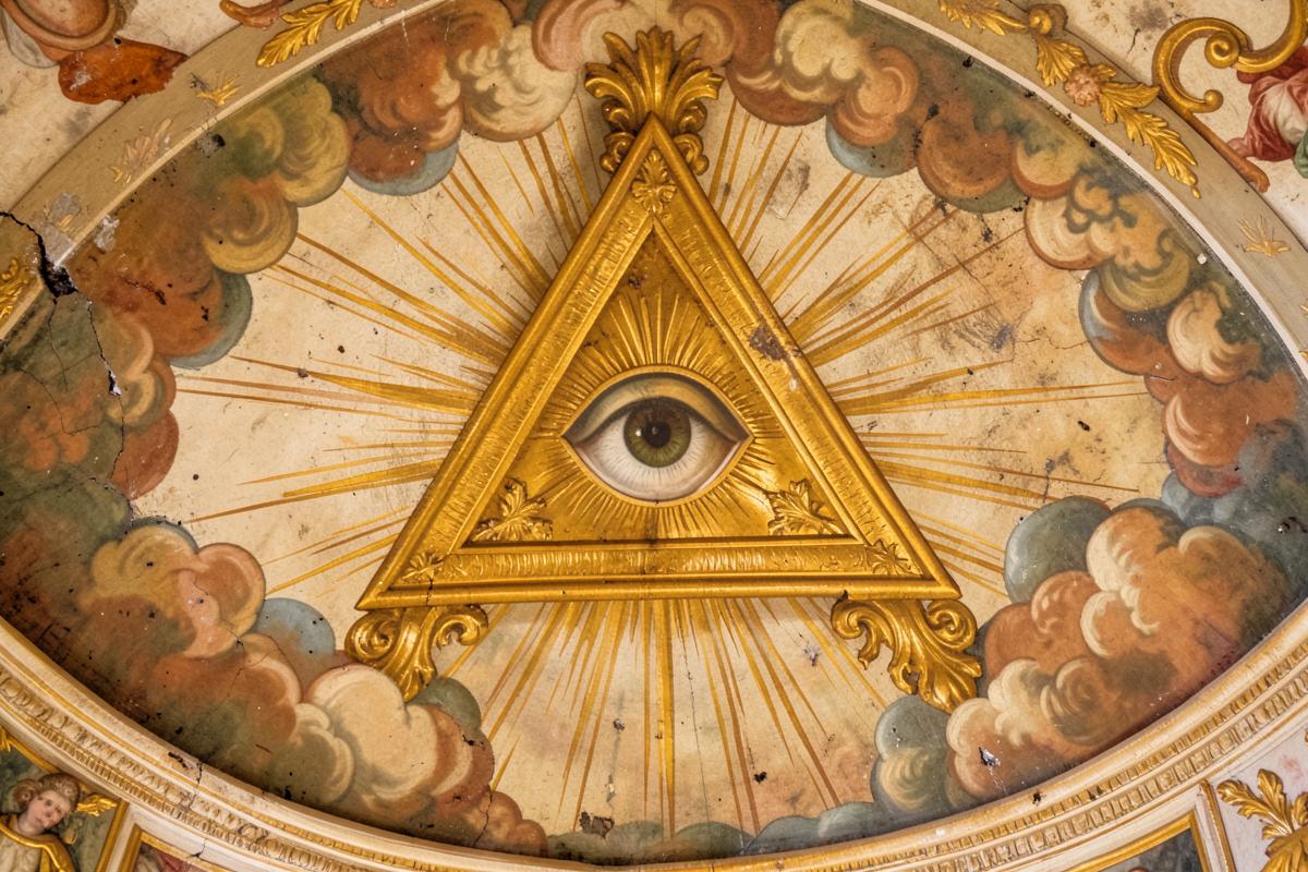 Pintura barroca no teto de uma igreja com o triângulo dourado e o olho entre nuvens e raios