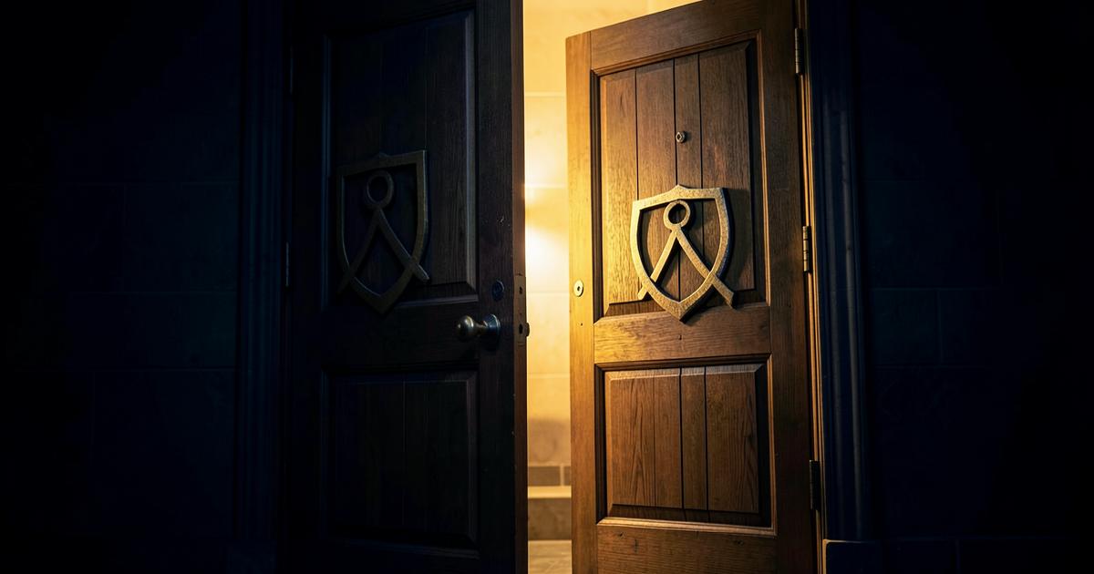 Porta de madeira de loja maçônica entreaberta com luz dourada e o símbolo do esquadro e compasso entalhado